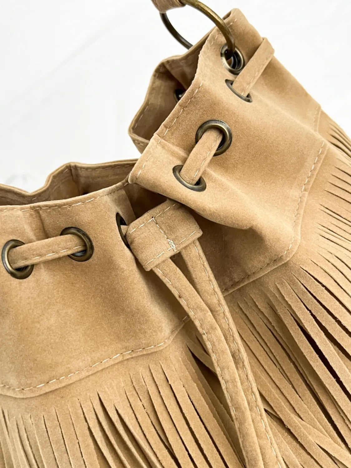 Bolso de hombro elegante en color beige con flecos y detalles metálicos para un look moderno