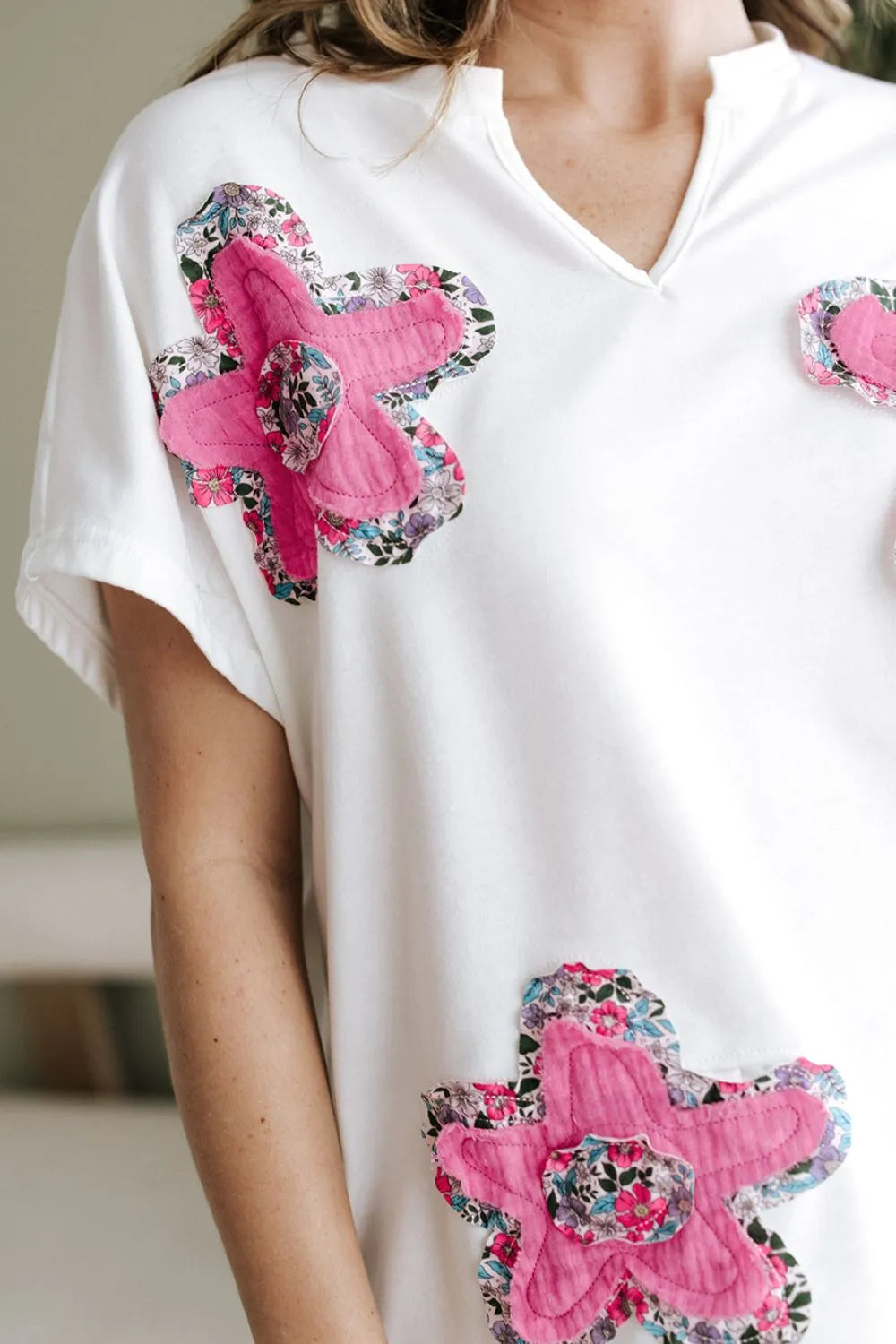 Blusa floral con mangas dolman de color blanco con flores rosas y detalles vibrantes