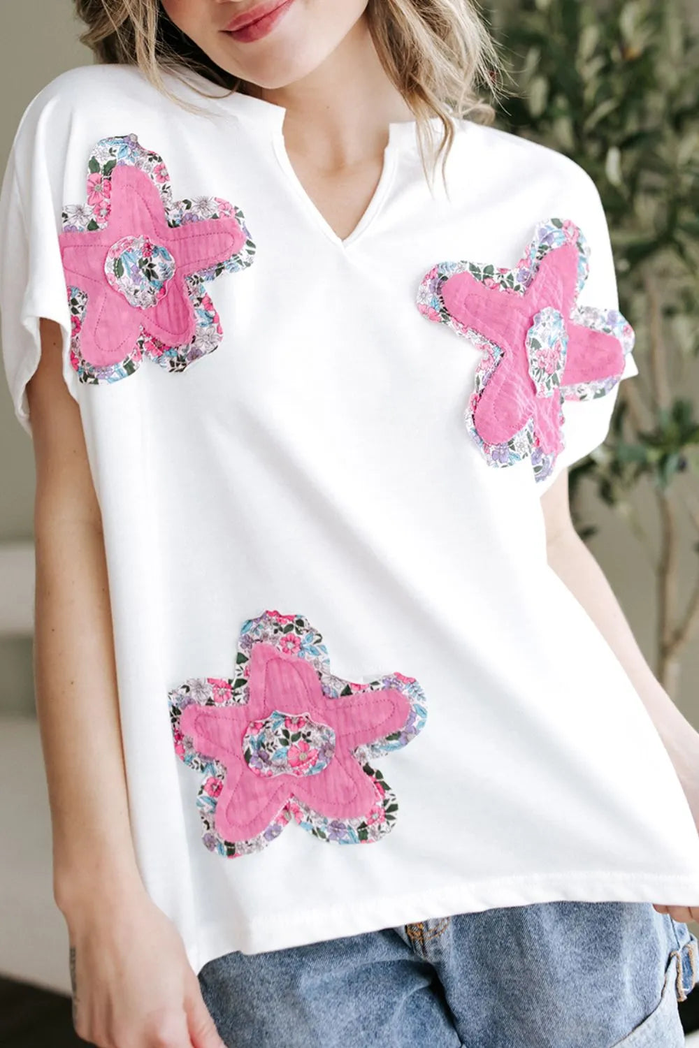 Blusa floral con mangas dolman en blanco con flores rosas y detalles coloridos