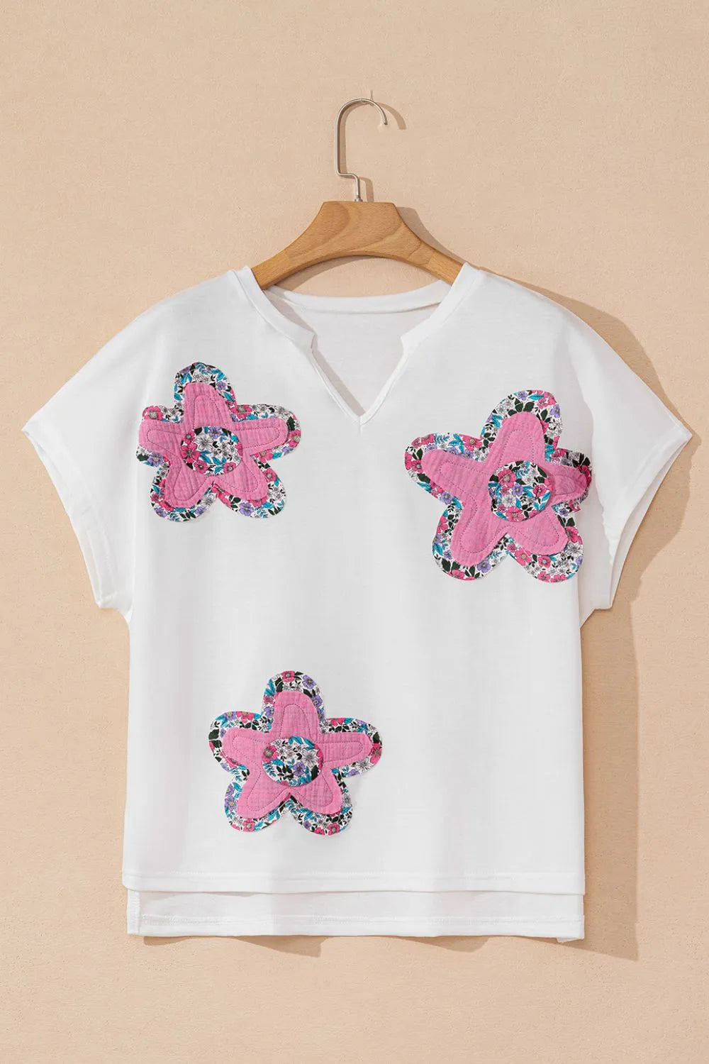 Blusa floral con mangas dolman en blanco con aplicaciones de flores rosas, ideal para verano.