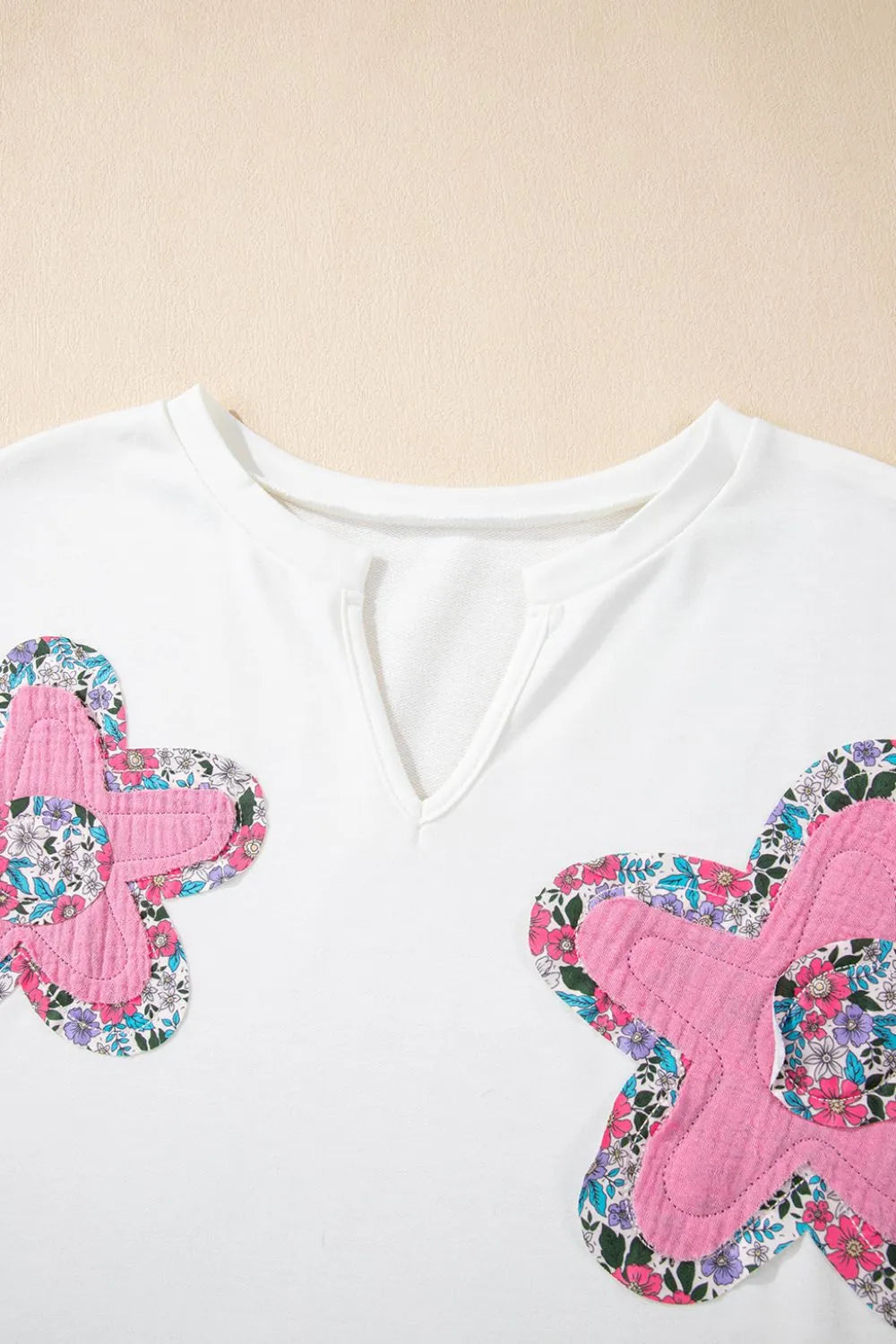 Blusa floral con mangas dolman en blanco con apliques de flores en tonos rosa y morado